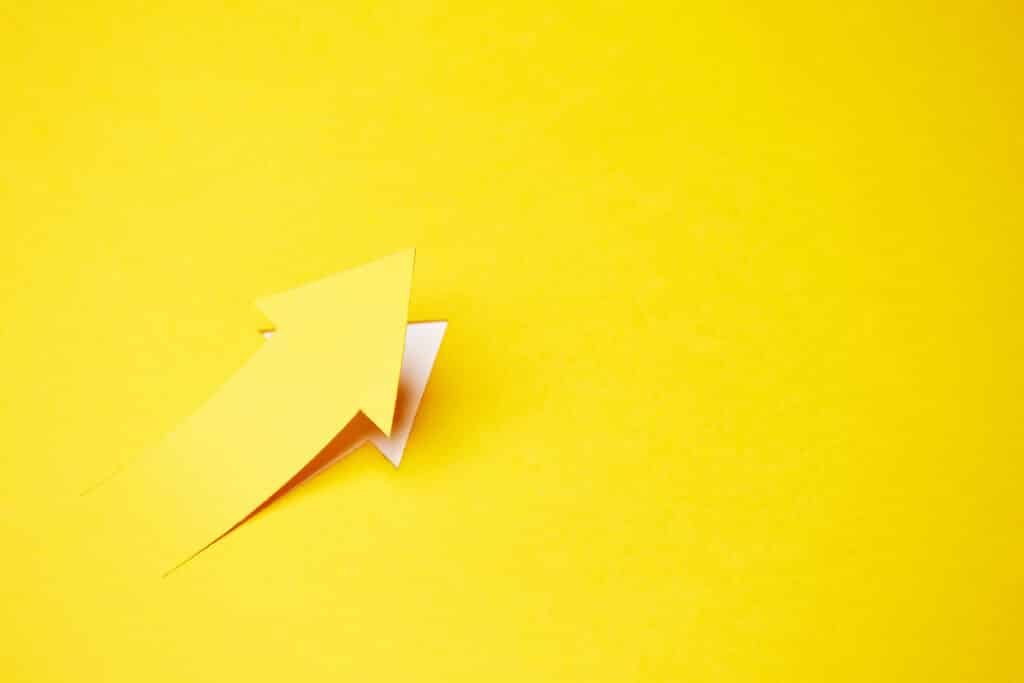 Right-up arrow cutted from solid sheet of yellow paper and curved up of one side with white paper underlay showing growth of stock market or up dental practice growth